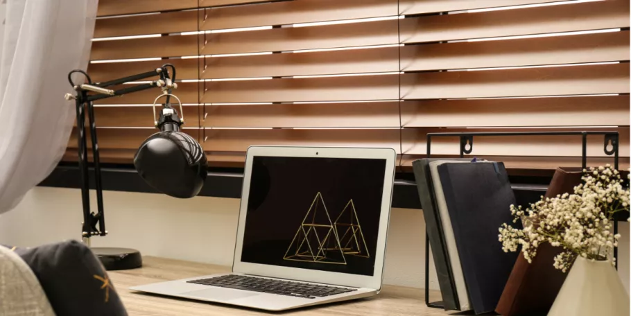laptop-at-desk-with-tan-wooden-blinds-behind
