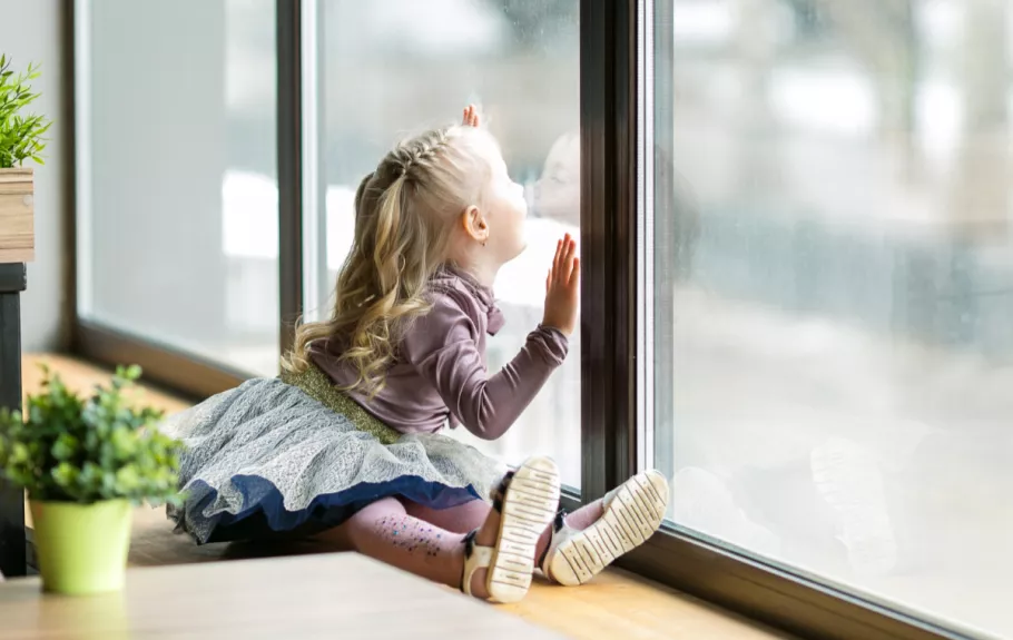 small-girl-with-hands-on-window-looking-out